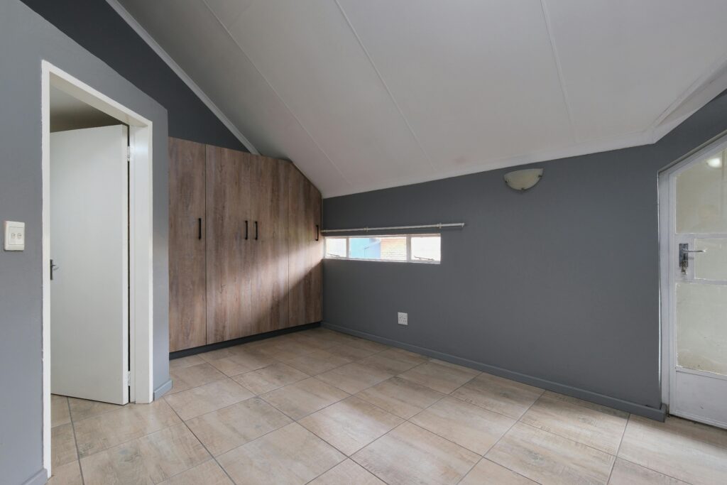 Spacious empty room with slanted ceiling and built-in wooden wardrobe offers a modern minimalist design.